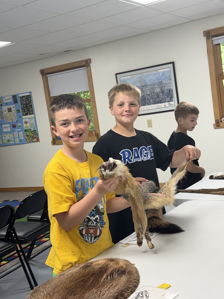 Two students are holding an animal pelt. 