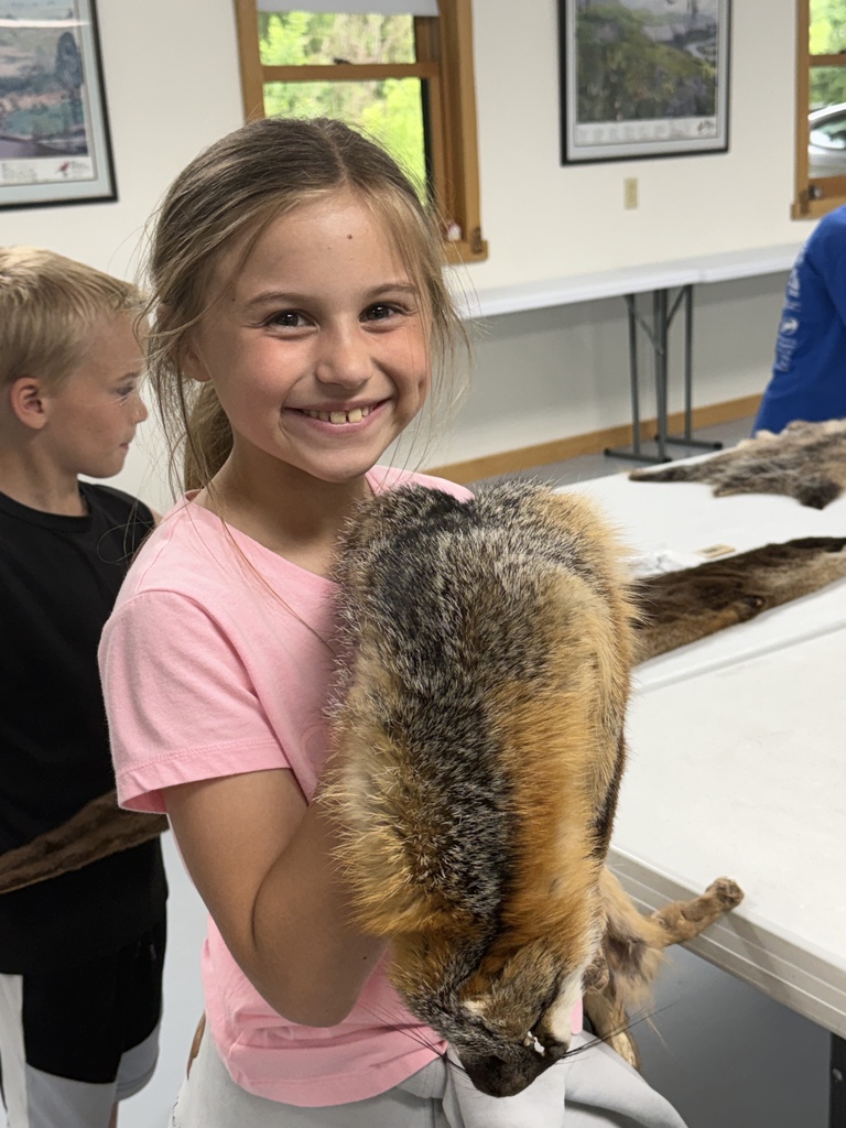 A student is holding an animal pelt. 