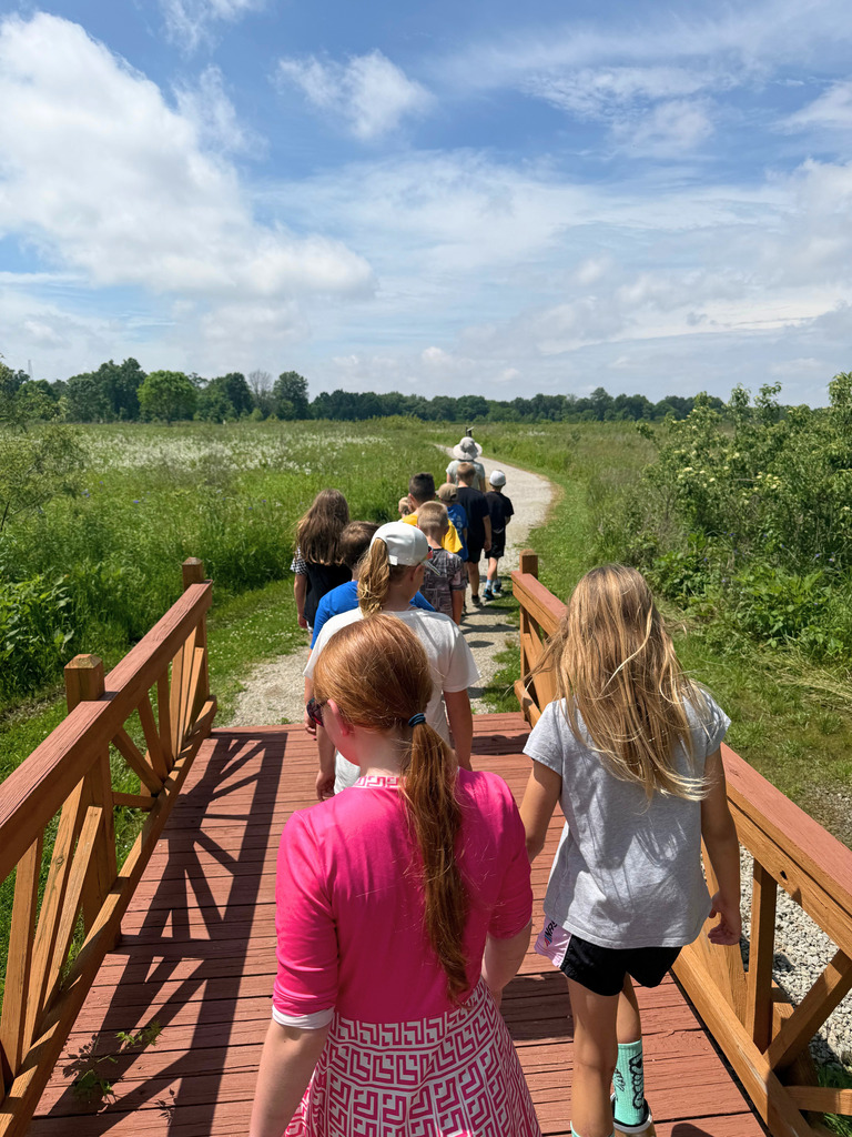 A class is following the guide on a trail at the center.
