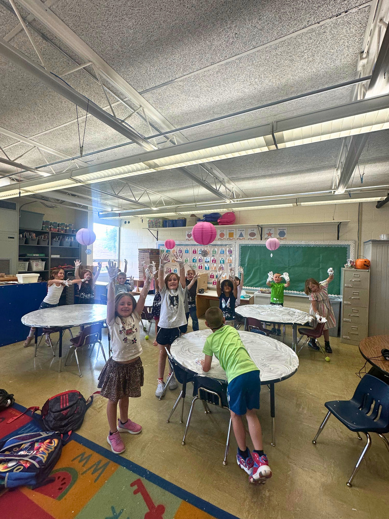 The class of students are standing with their hands in the air. They are covered with shaving ceam.