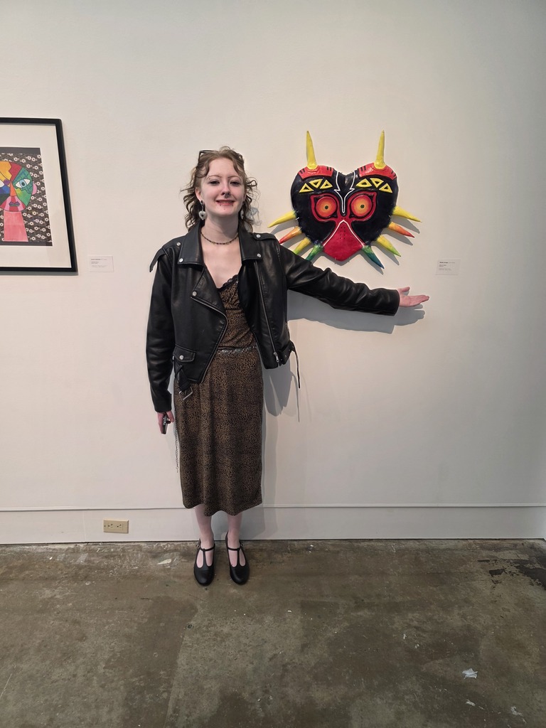 A student is standing next to their artwork,. 