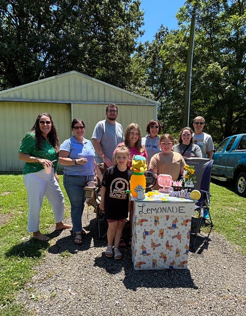 Pictured is JB and her lemonade stand surrounded by six school employees and siblings. 