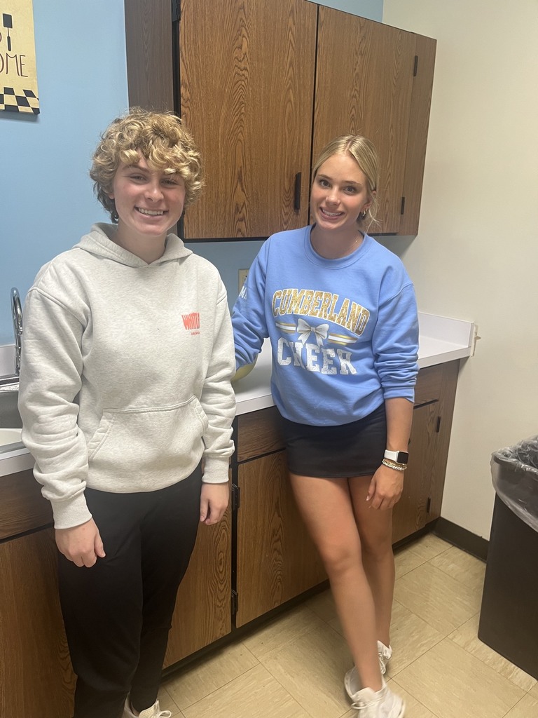 Two students are standing against the kitchen counter facing the camera. 