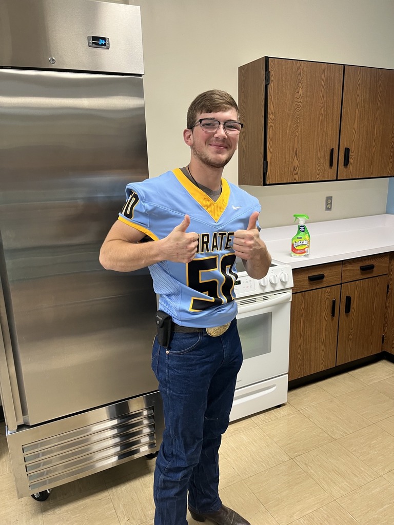A student is standing in the kitchen with two thumbs up. 