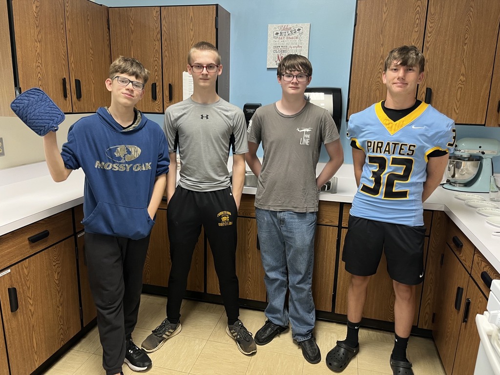 Four students are standing in the kitchen together.