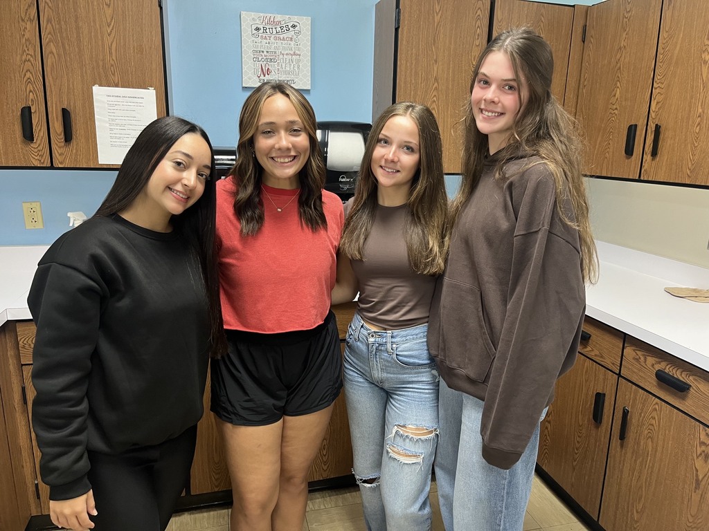 Four students are standing in the kitchen together. 
