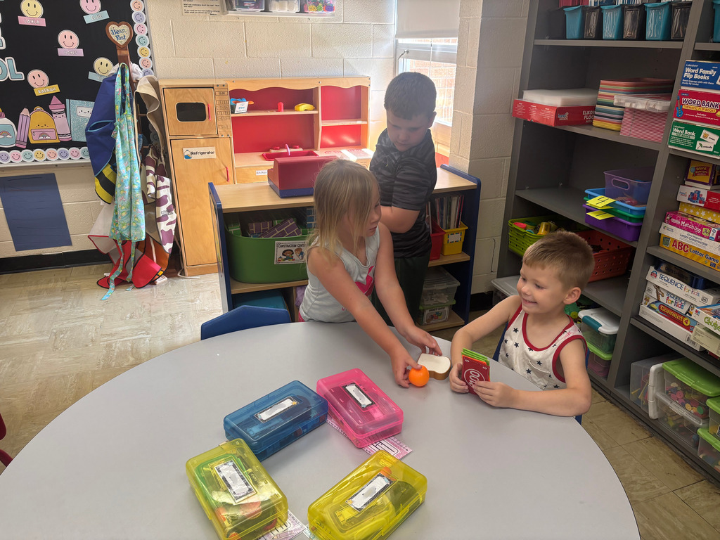 Three students are playing store at their table.