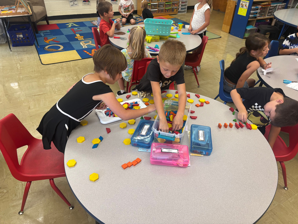 Three students are playing with blocks at their table.