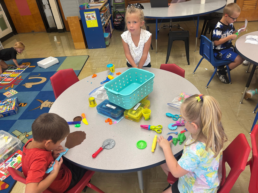 Three students are playing with play-doh at their table.