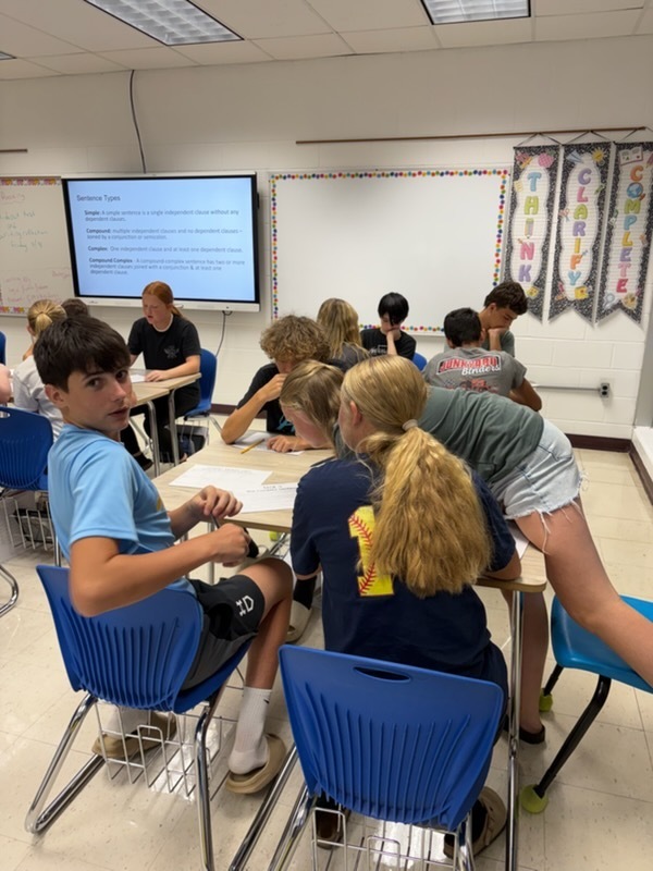Students are working at their desks in groups to work out  problems to excape the room.