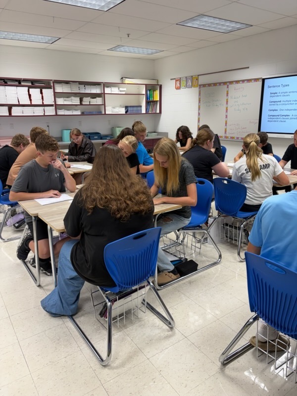 Students are working at their desks in groups to work out  problems to excape the room.