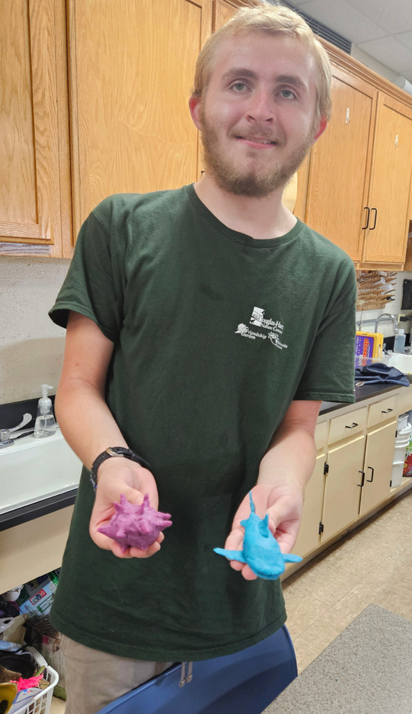A student is holding their symetrical animal made out of play-doh.