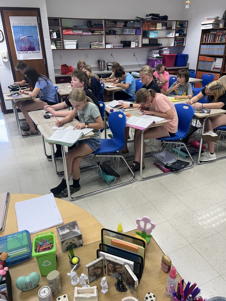 Students are sitting at their desks writing events from the story down on notecards. 