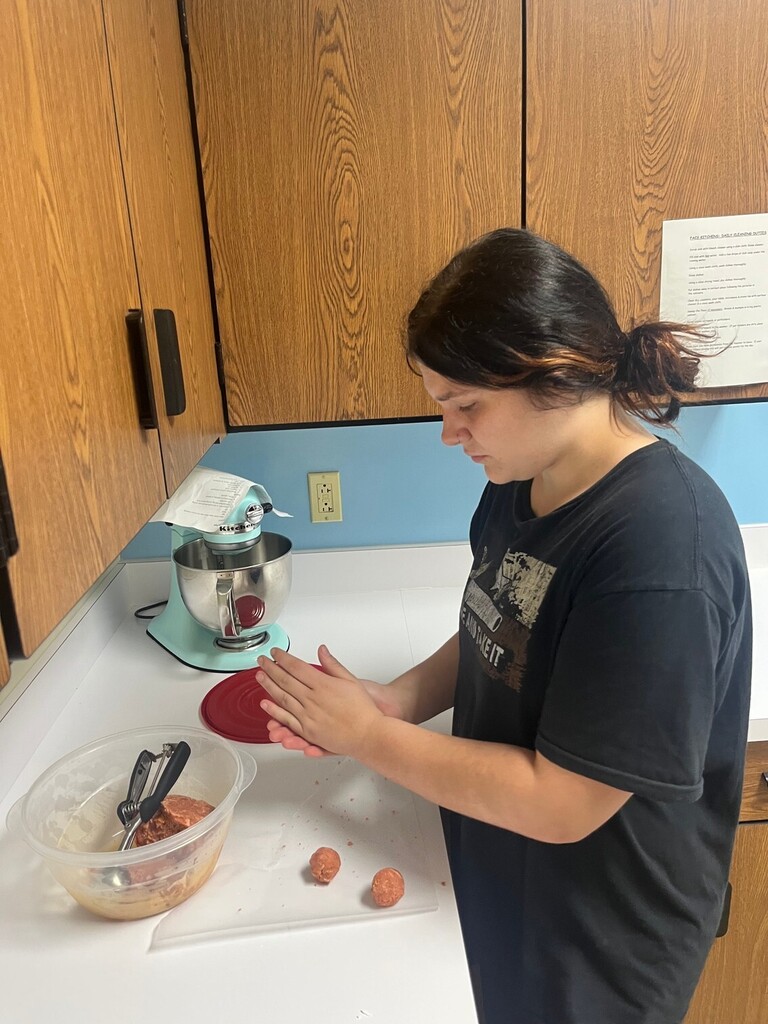 A student is rolling cake dough in their hands. 