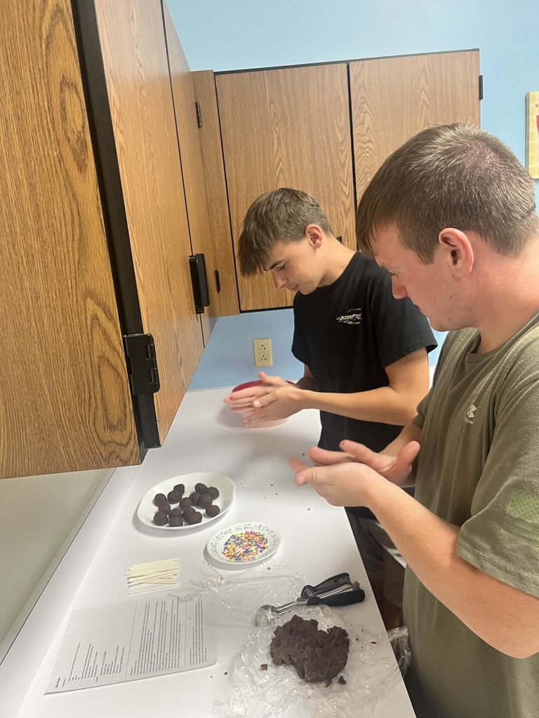Two students are rolling the cake dough in their hands. 