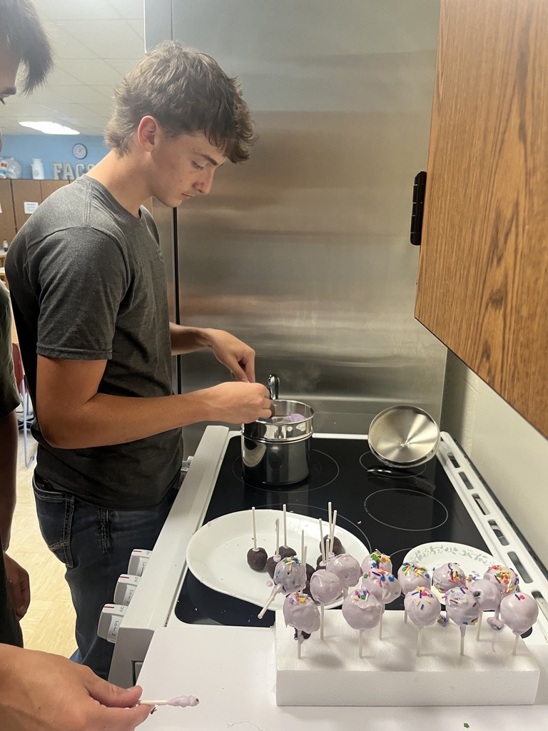A student is dipping a cake pop into the double broiler. 