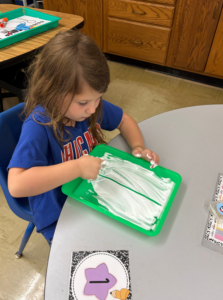 A student is writing a number on a tray covered in shaving cream.