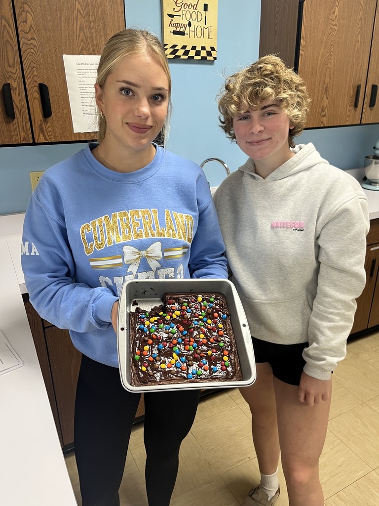 Two students are standing together. They are holding a pan of brownies. 