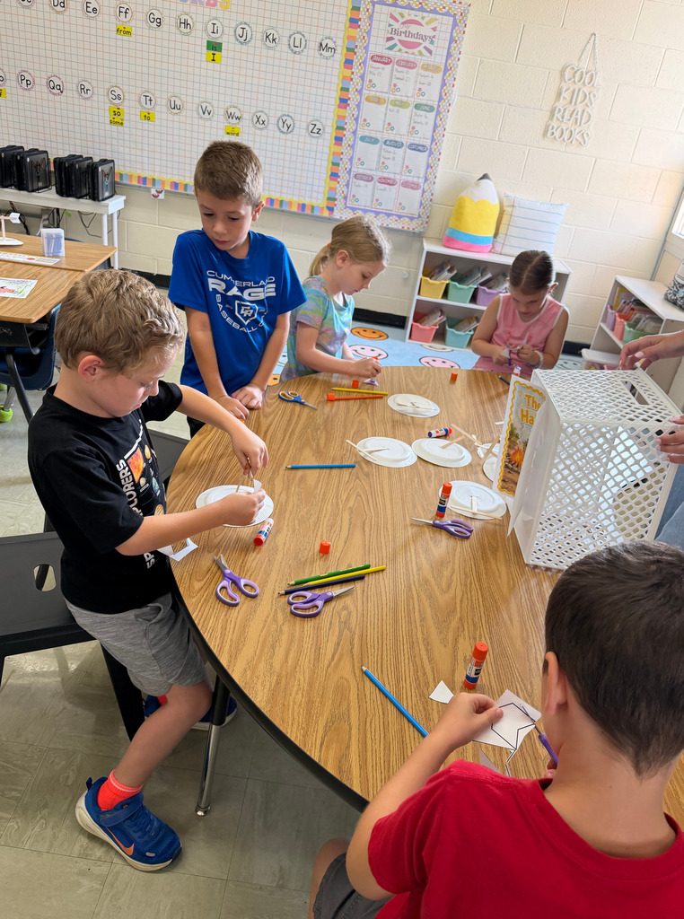 Students are cutting paper at a table. 