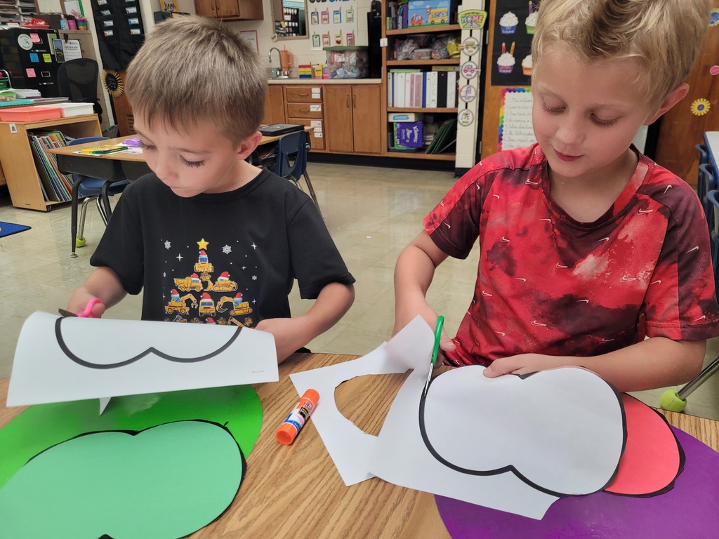 Two students are cutting apple shapes.