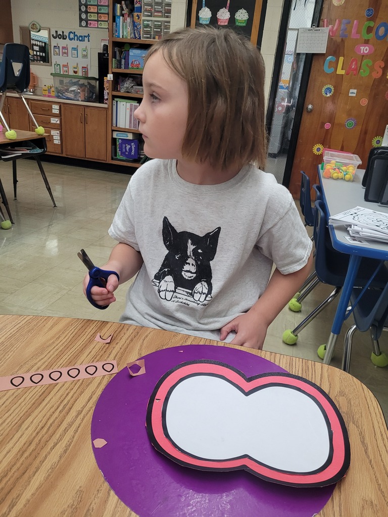 A student is holding scissors. The student is looking away from the project.