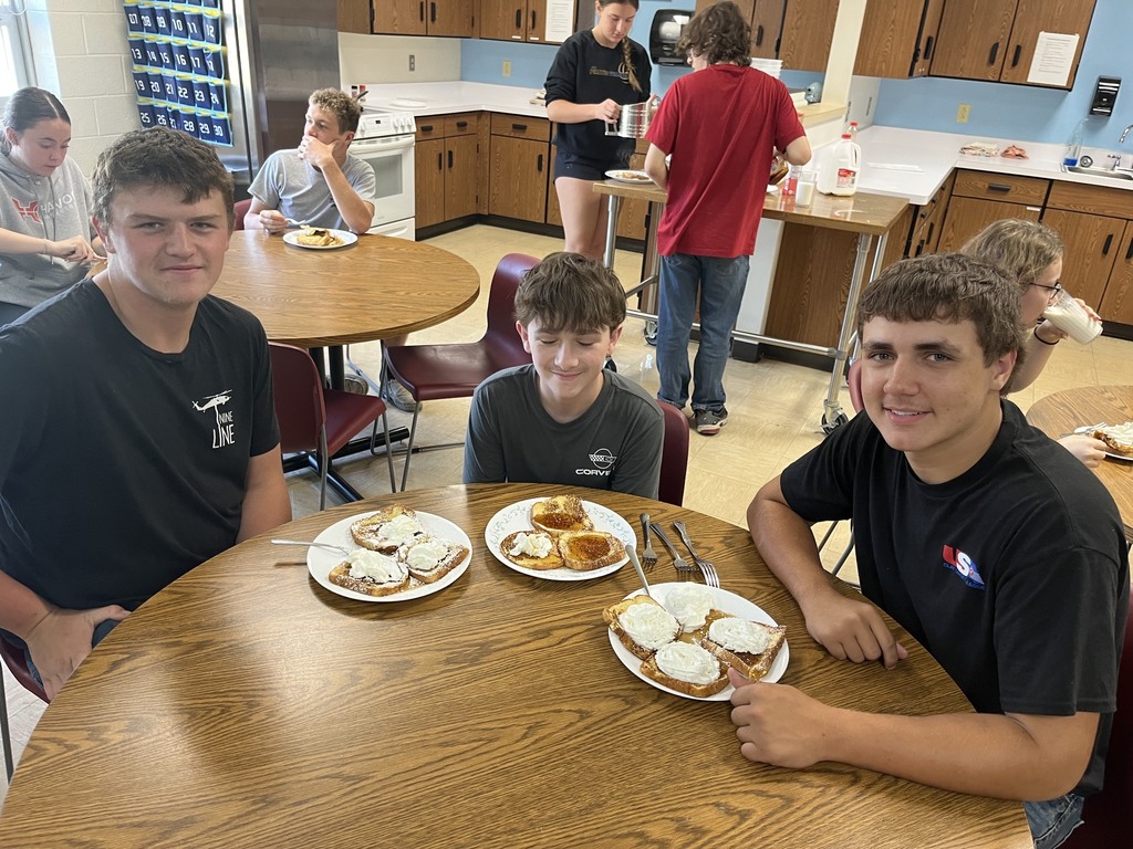 Tjree stidemts are sitting at a table with plates of French toast.