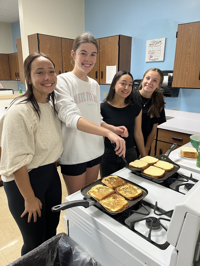 A student is flipping the French toast. Three others are watching.