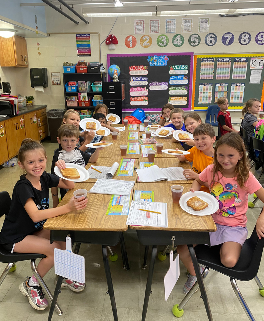 Students are sitting at their desks with plates of toast and drinks of tea.