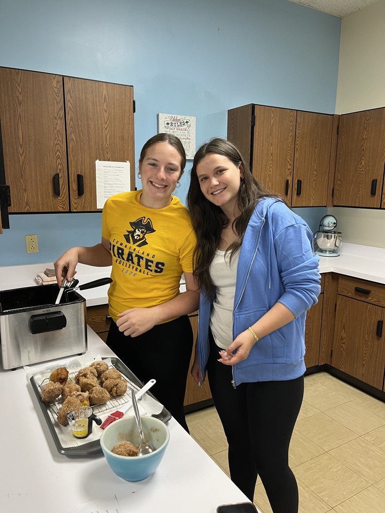Two students are taking donuts out of the fryer.
