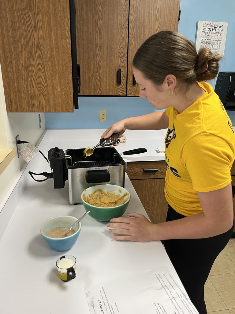A student is dipping batter into the fryer.