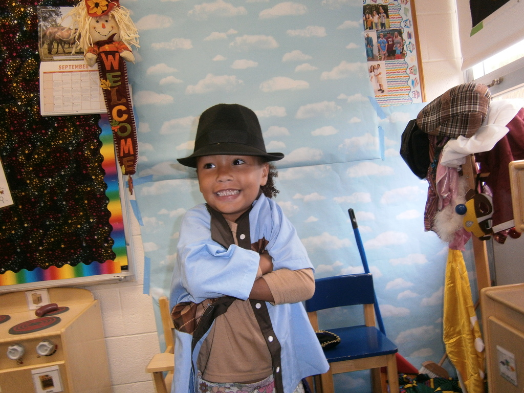 A student is wearing a derby hat and crossing their arms. 