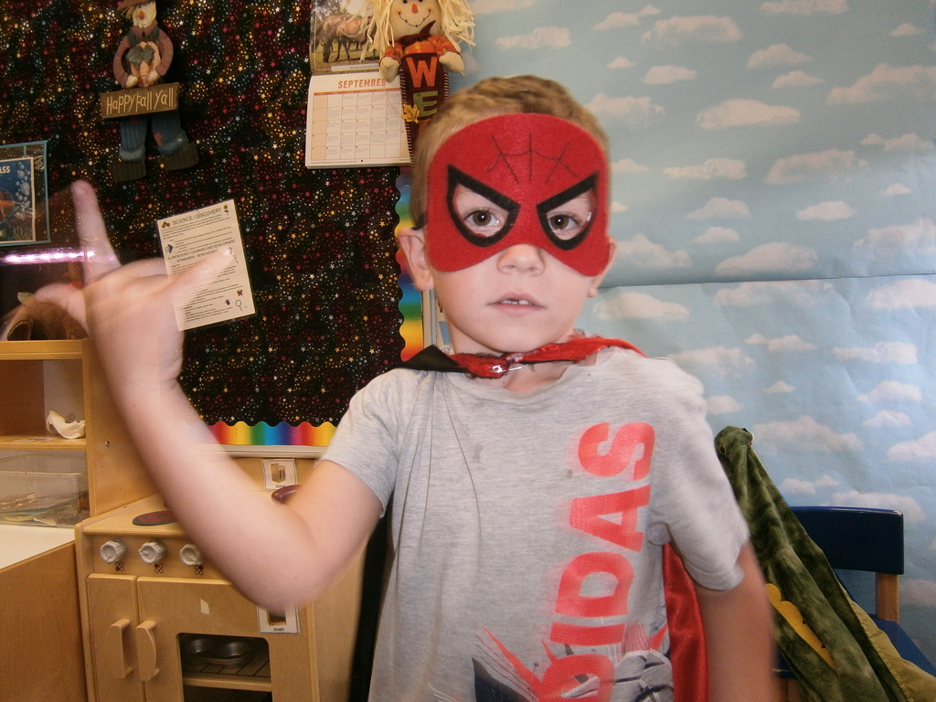 A student is wearing a spiderman costume and posing their hand like spiderman.