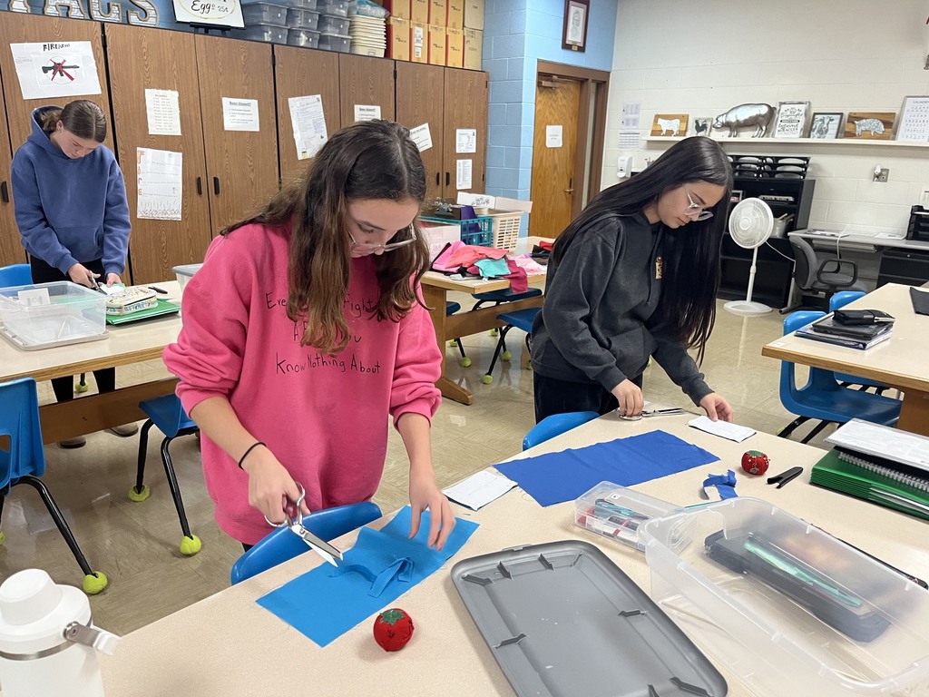 Two students are cutting their fabric pieces. 