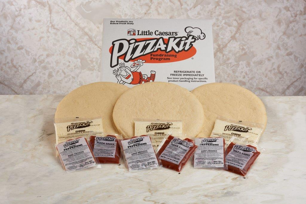 Pictured is a Little Caesars Pizza Kit. It show the box, three pizza crusts, cheese, sauce, and toppings.
