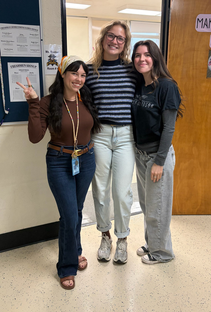 Three staff members are dressed in decade-themed outfits. 