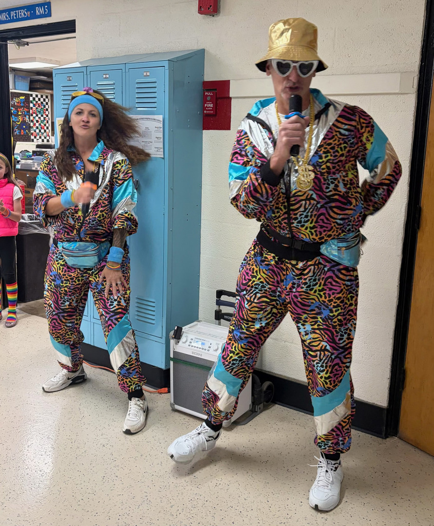 Two staff members are dressed in decade-themed outfits. 