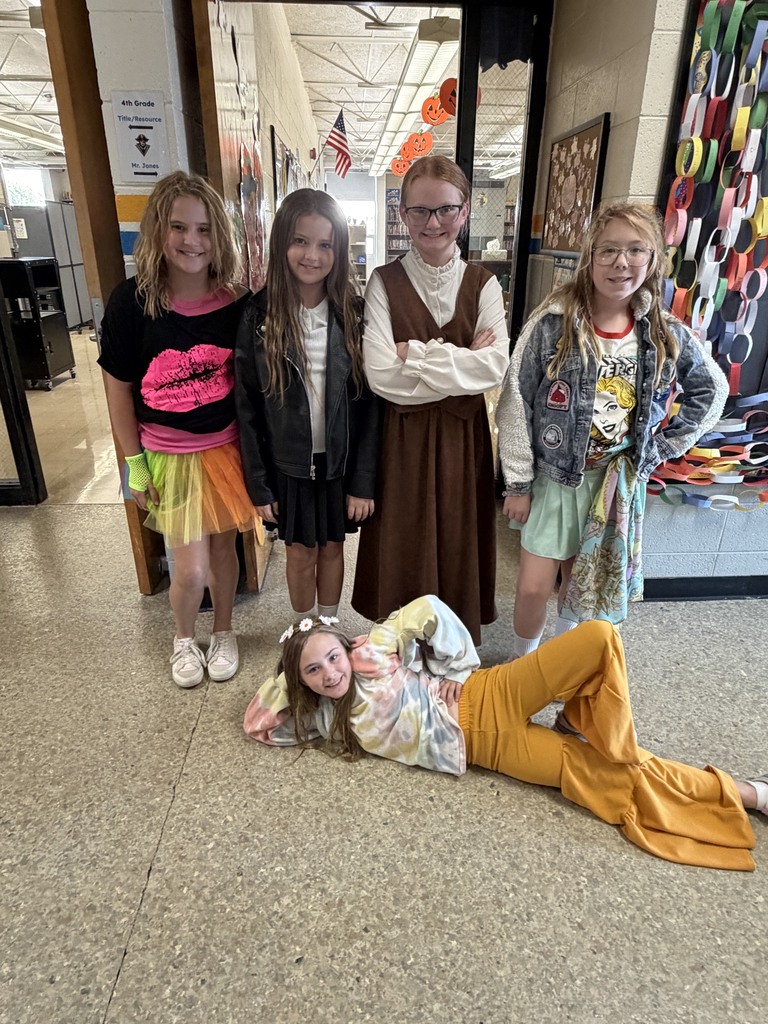 Five students are dressed in decade-themed outfits. 
