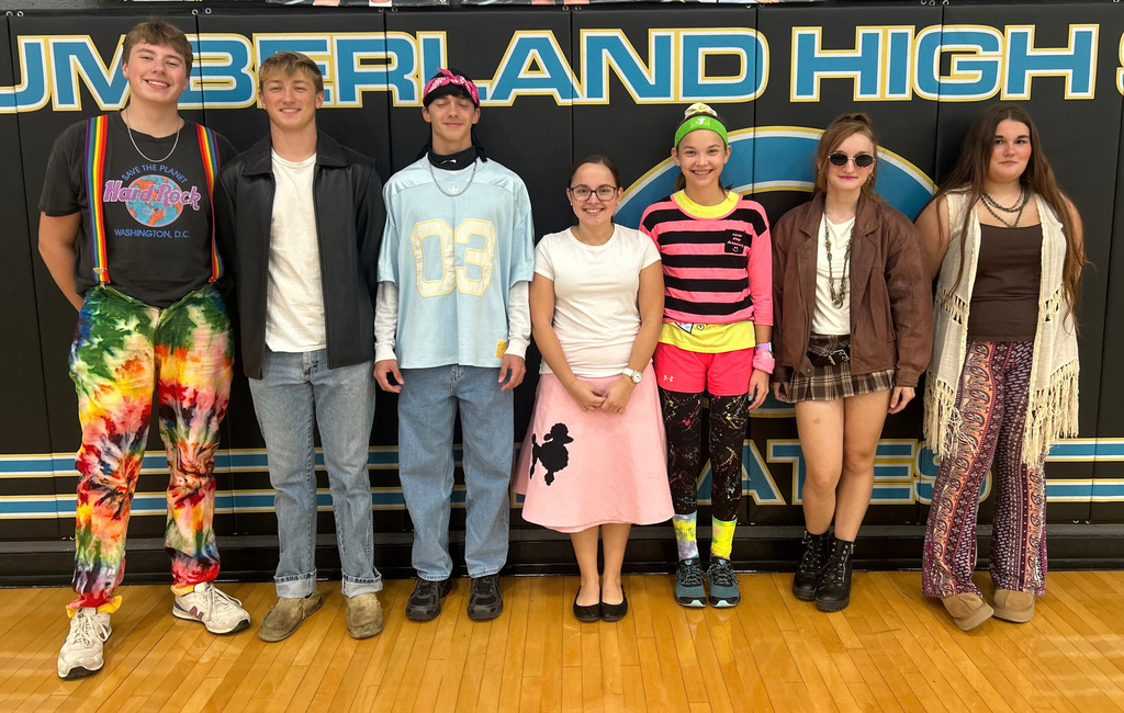 Seven students are dressed in decade-themed outfits. 