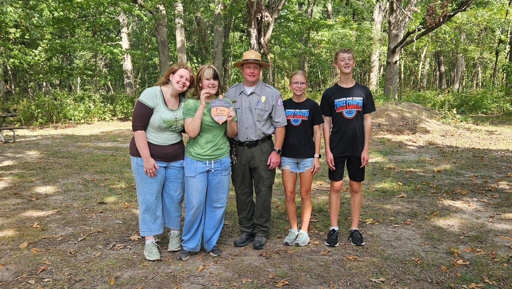 The four members are standing with the park representative with their plaque. 