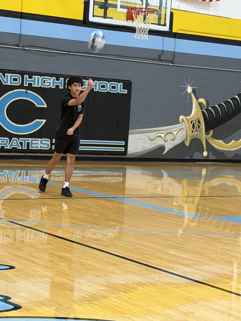 A team dressed in black is playing volleyball. One player has served the ball. 