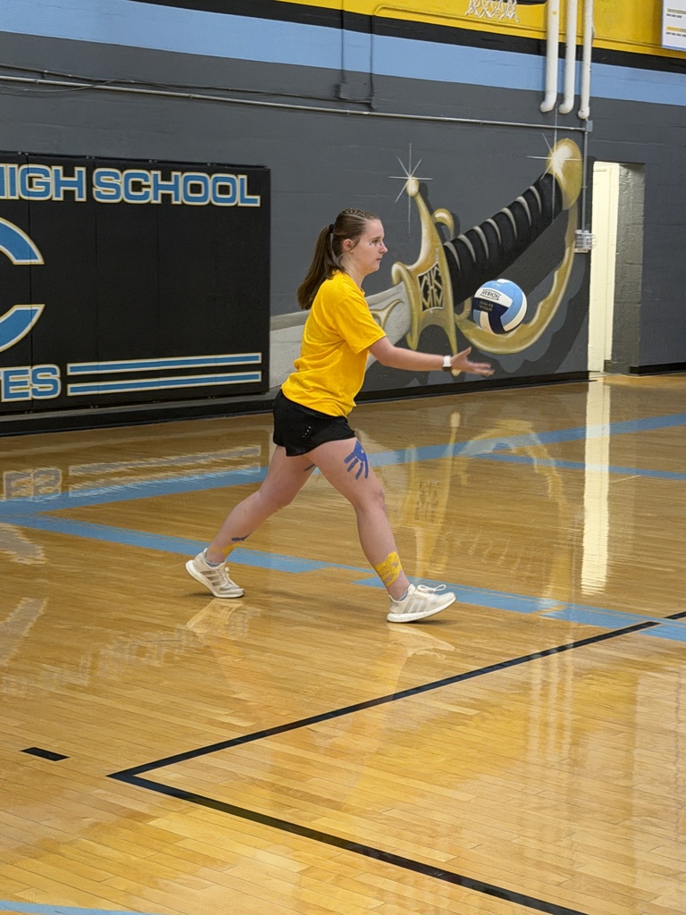 A team dressed in yellow is playing volleyball. One player has served the ball. 