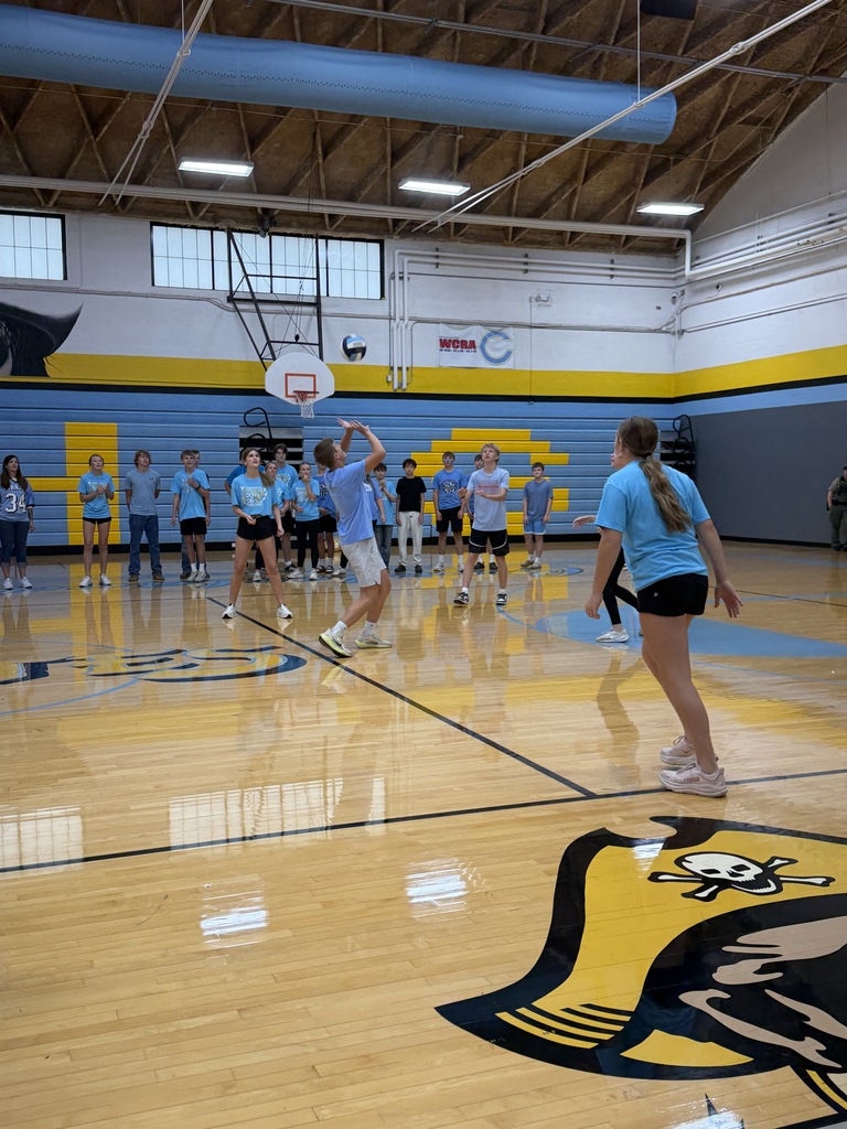 A team dressed in blue is playing volleyball. One player has setted the ball. 