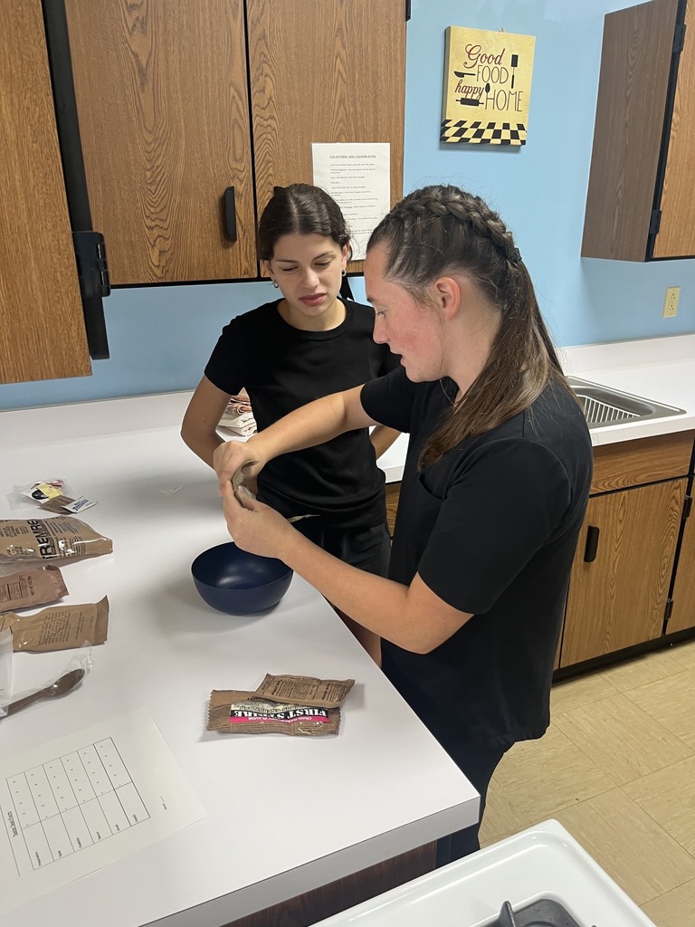 One student is opening an MRE while another is watching.