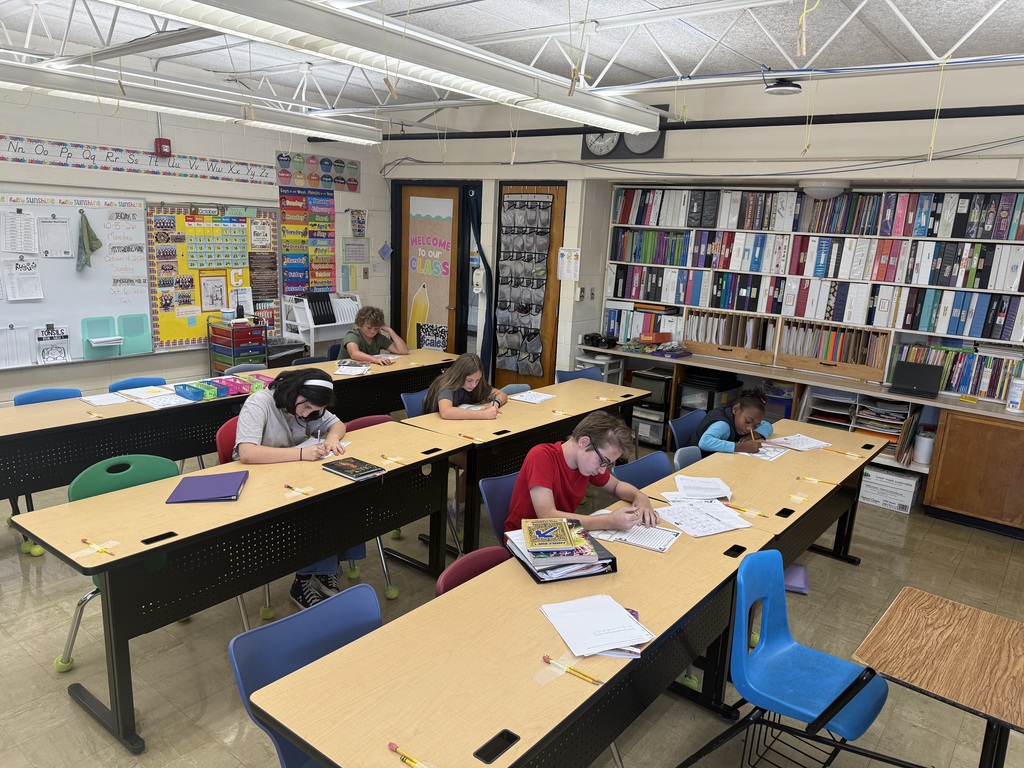 Students are sitting at their desks working on their writing. 