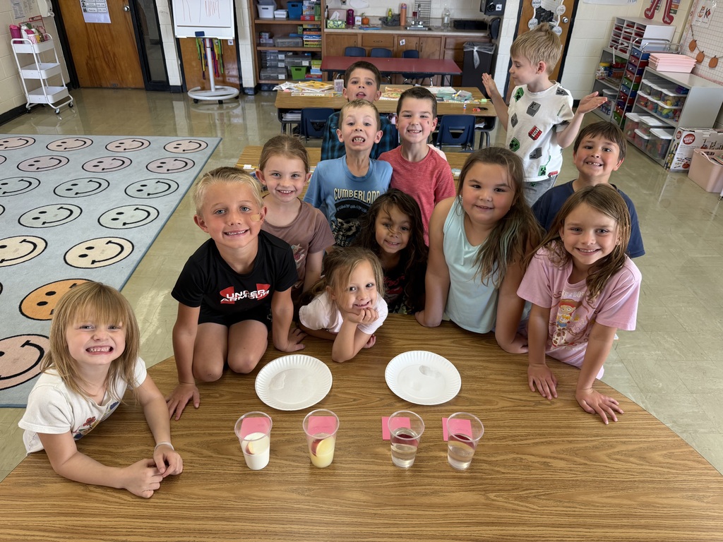 Students are standing behind a table where the apple cups are. 