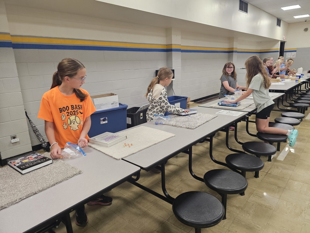 Students have a square of carpet that they are rubbing a book on. 