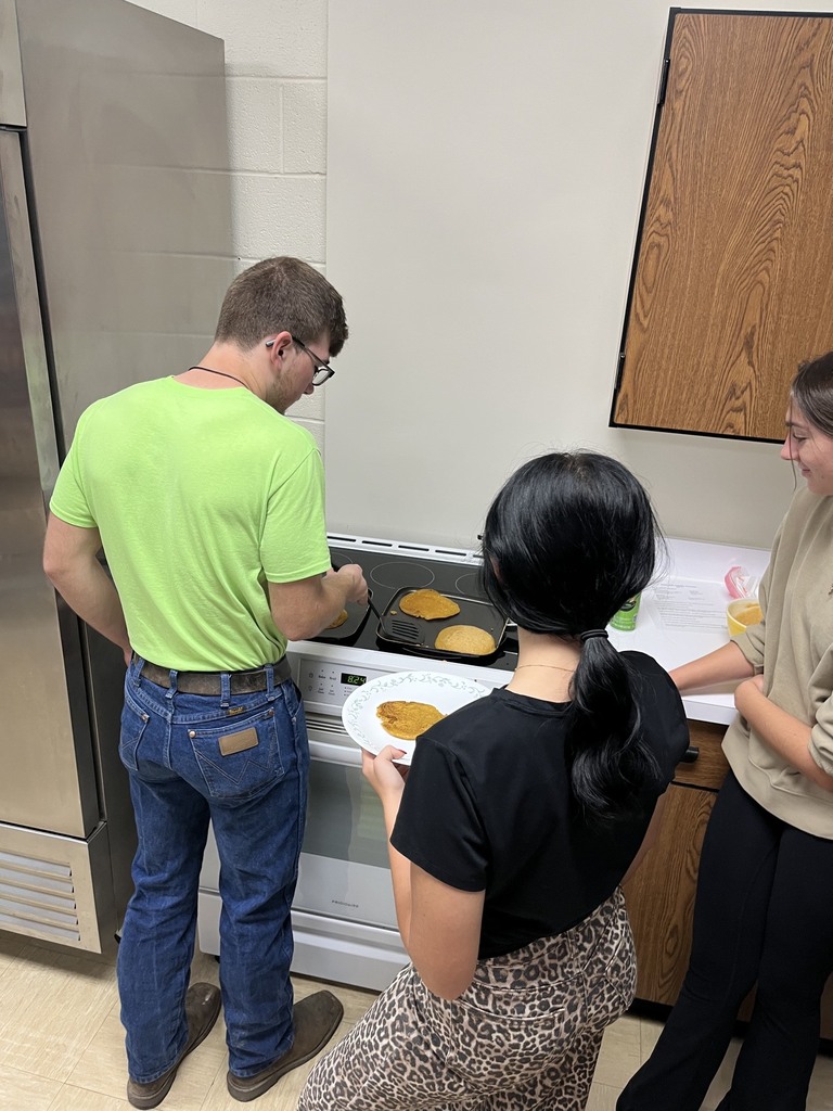 Three students are watching their pancakes cook.