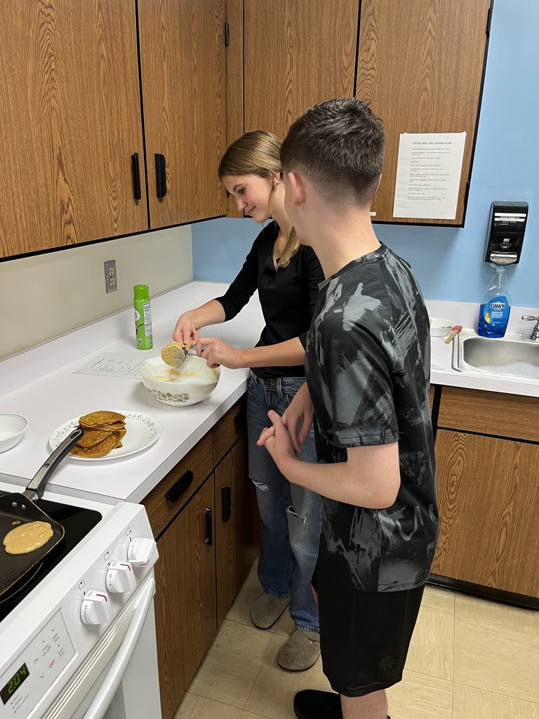 Two students are adding whipped cream to the pancakes.