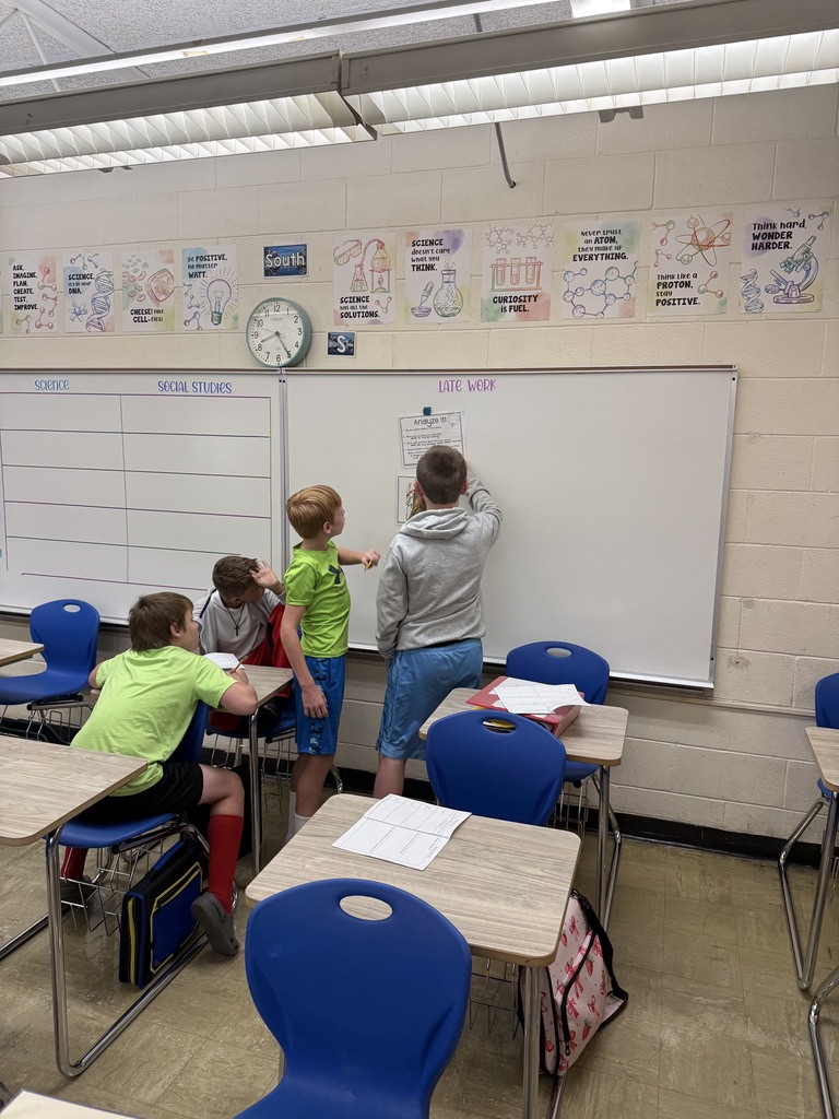 A group of four students is at an area of the room filling out a  packet together. 