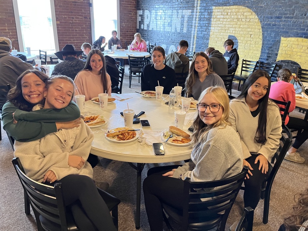 Seven students are sitting at a round table finishing their meal.